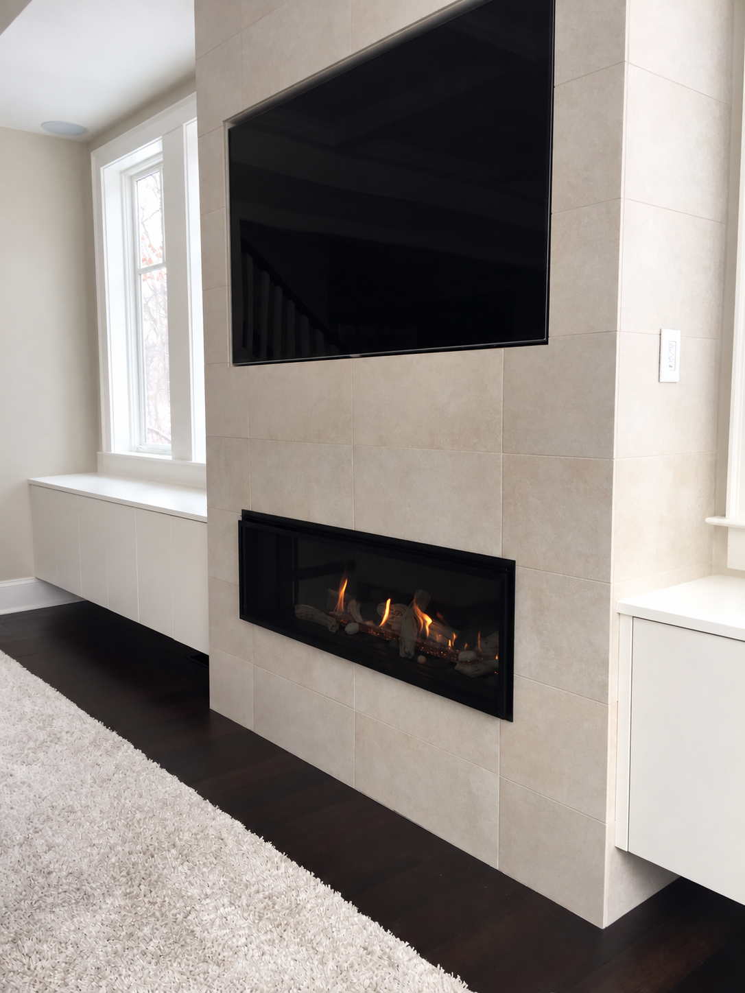 A contemporary gas fireplace set into a light stone wall